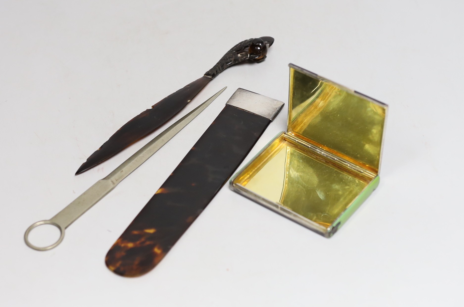 An Art Deco silver and two colour enamel cigarette case, import marks for H.C. Freeman Ltd, London, 1936, 82mm (a.f.), a small silver dish engraved with a dog, two tortoiseshell letter openers and a plated meat skewer.